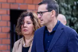Iwona i Mateusz Morawieccy w zbliżeniu, na tle ceglanego muru.