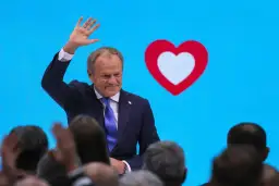 Donald Tusk macha do tłumu na tle niebieskiego ekranu z sercem. Czy to koalicja?