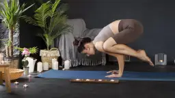 Kobieta w pozycji jogi na macie, otoczona świecami i roślinami.