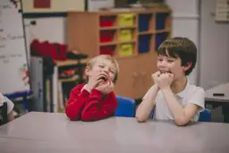 Dwóch chłopców śmieje się wesoło w klasie. Ich oceny z zachowania w szkole z pewnością będą wysokie!