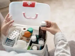 Otwarta apteczka samochodowa z lekami, plastrami i bandażami.