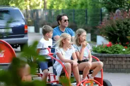 Marcin Dorociński z dziećmi na przejażdżce pojazdem gokartowym.