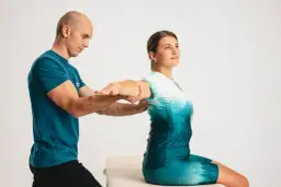 Fizjoterapeuta pomaga pacjentce w rehabilitacji ręki po złamaniu kości promieniowej, wykonując ćwiczenia zakresu ruchu.