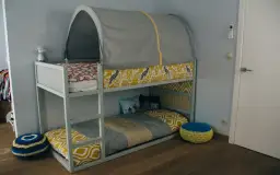 Urocze łóżko piętrowe z namiotem i kolorowymi aranżacjami. Kura na pościeli dodaje uroku.