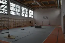 Wnętrze hali sportowej w budowie, z drabinkami, koszem i bramką. Zastanawiasz się, ile kosztuje budowa hali sportowej?