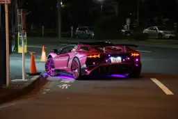 Różowy Lamborghini z neonowym podświetleniem na ulicy nocą.