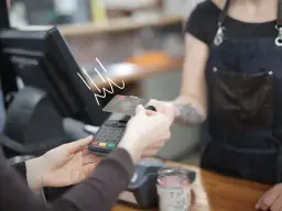 Zbliżenie na płatność kartą debetową przy terminalu płatniczym.