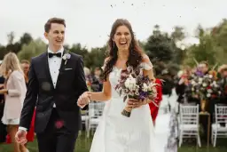 Szczęśliwa para młoda idzie alejką, obsypana płatkami. Zastanawiasz się, o co pytać fotografa na wesele?