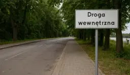 Znak "Droga wewnętrzna" przy alei drzew. Definicja drogi wewnętrznej jest jasna: to droga niepubliczna, zarządzana przez właściciela terenu.