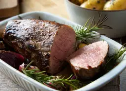 Pieczony stek z cielęciny z rozmarynem i cebulą w naczyniu żaroodpornym.