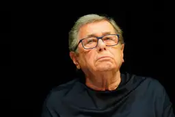 Portret Janusza Gajosa w okularach na czarnym tle.