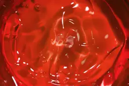 Czerwona galaretka z pęcherzykami powietrza i błyszczącymi refleksami.