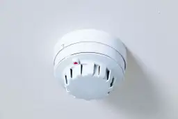 Biały czujnik czadu na suficie, z czerwoną diodą, która pika co jakiś czas, sygnalizując bezpieczeństwo.