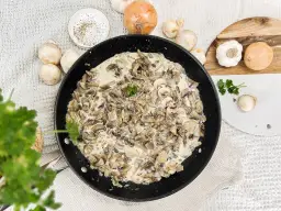Kremowy sos pieczarkowy na patelni, idealny do makaronu, ziemniaków czy mięsa. Obok składniki: pieczarki, cebula, czosnek, natka pietruszki.
