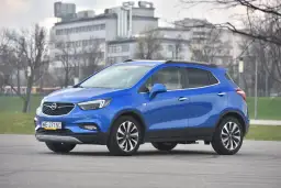 Niebieski Opel Mokka stoi na drodze, w tle budynki i drzewa.