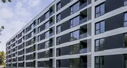 Nowoczesny blok mieszkalny z balkonami i dużymi oknami. Czy mieszkanie komunalne można wynająć w takim miejscu?