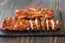 Soczyste, glazurowane żeberka wieprzowe, pokrojone na kawałki. Idealne do grillowania, zastanawiasz się, jak długo wędzić polędwiczki wieprzowe, by osiągnąć taki efekt?