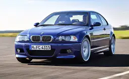Niebieskie BMW M3 E46, ikona motoryzacji z lat produkcji 2000-2006, pędzi po drodze.