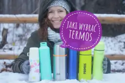 Kobieta w zimowym ubraniu trzyma kilka kolorowych termosów na śniegu.