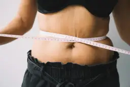 Kobieta mierzy talię centymetrem. Czy to początek drogi, jak szybko schudnąć 20 kg?