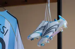 Białe korki z niebieskimi i złotymi detalami, wiszące obok koszulki z napisem "MESSI". To w takich korkach grał Messi, świętując 10-lecie.