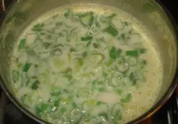 Gotująca się zupa z zielonej cebulki w garnku.