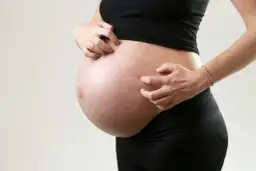 Ciężarna kobieta drapie brzuch, co może być jednym z objawów cholestazy ciążowej.