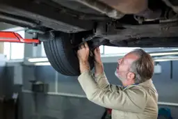 Mechanik sprawdza podwozie samochodu i koło.