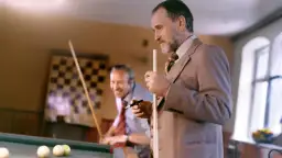 Dwóch mężczyzn gra w bilard. Scena przypomina miejsce, gdzie kręcono "Wielkiego SzU".