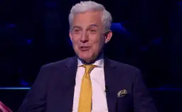 Prowadzący w garniturze z żółtym krawatem, jakby zapowiadał specjalne wydanie "Milionerzy Walentynki gdzie obejrzeć".