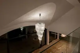 Olśniewający, wielopoziomowy żyrandol z kryształkami, idealny jako żyrandol do salonu, w nowoczesnym wnętrzu z łukowym sufitem.