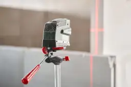 Poziomica laserowa na statywie z czerwonymi liniami wyznaczającymi idealny ranking poziomic laserowych.