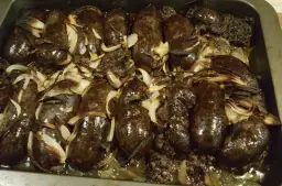 Kaszanka pieczona w piekarniku z cebulą, apetycznie przyrumieniona, gotowa do podania.