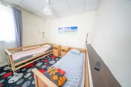 Pokój z dwoma łóżkami, szafkami nocnymi i kolorowym dywanem.