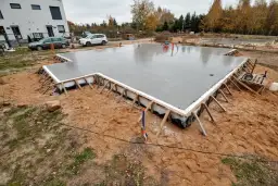 Świeżo wylana płyta betonowa na budowie. Czy tańsze płyta czy fundament? Widać zbrojenie i szalunki.