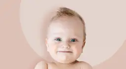 Uśmiechnięte niemowlę z niebieskimi oczami na jasnoróżowym tle.