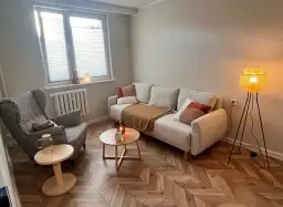 Przytulny gabinet terapeutyczny z sofą, fotelem i lampą.