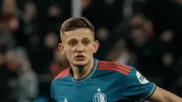 Młody piłkarz w niebieskiej koszulce z czerwonymi pasami na ramionach, z emblematem Feyenoordu. Czy to **kitman, kto to**?