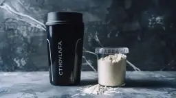 Czarny shaker i pojemnik z białym proszkiem. To suplementy, które pomogą Ci zrozumieć, cytrulina co daje.