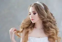 Piękna panna młoda z burzą złotych loków i delikatną tiarą. Jej fryzura fale na wesele jest idealna na ten wyjątkowy dzień.