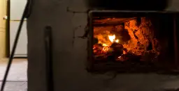 Płonące drewno w palenisku pieca na ekogroszek.