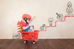 Dziecko w wieku przedszkolnym w koszyku na kółkach, z rakietą na plecach, symbolizuje rozwój fizyczny i wyobraźnię.