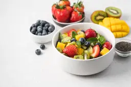 Kolorowa sałatka owocowa z truskawkami, kiwi, mango i borówkami. Idealna na zdrową przekąskę, zawiera owoce o niskim indeksie glikemicznym.