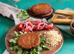 Kotlety burgerowe z pomidorami, cebulą i kaszą na drewnianej desce.