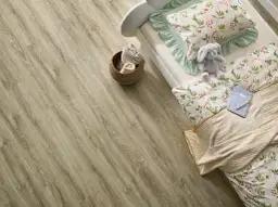 Łóżko z pluszowym królikiem i pościelą w kwiaty na podłodze z paneli winylowych. Czy panele winylowe są zdrowe? Tak, są bezpieczne dla dzieci.