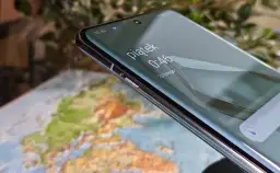 Zbliżenie na ekran telefonu z widocznym zegarem i mapą w tle.