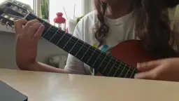 Osoba gra na gitarze klasycznej, ćwicząc znane utwory na gitarę klasyczną.