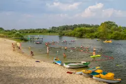 Wola Uhruska tętni życiem. Ludzie kąpią się, pływają na łódkach i relaksują na piaszczystej plaży.