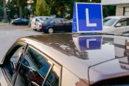 Niebieska tablica z literą "L" na dachu samochodu nauki jazdy.