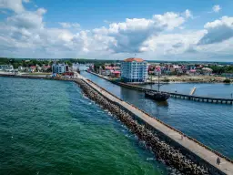 Port w Darłowie z falochronem, statkiem pirackim i nowoczesnym budynkiem. Atrakcje turystyczne na wyciągnięcie ręki.